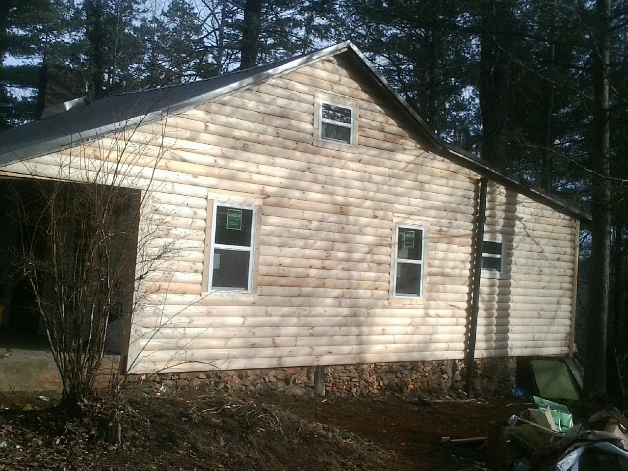 New log siding and dark metal roofing on a gable end in Homer